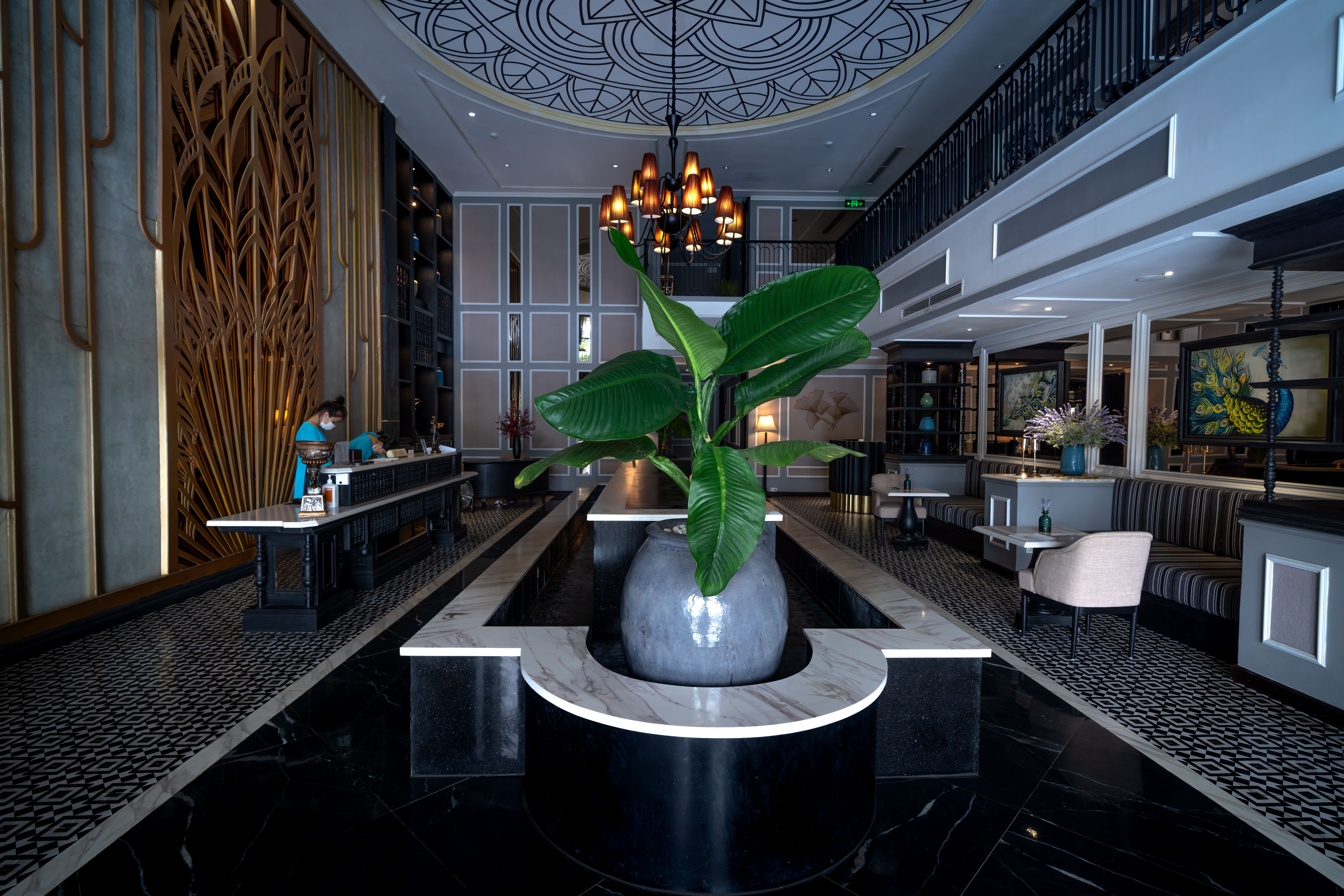 Stylish hotel lobby with a chandelier and central plant arrangement, illustrating an inviting visual for hotel marketing.